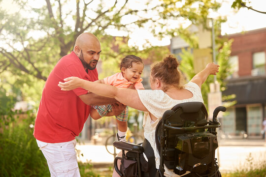Father flying young child into arms of disabled mother.