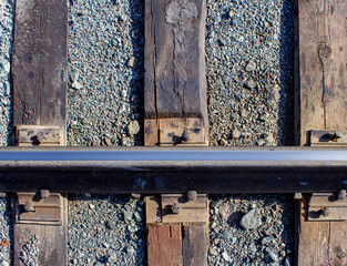 A metal rail is bolted to three wooden sleepers. Close-up