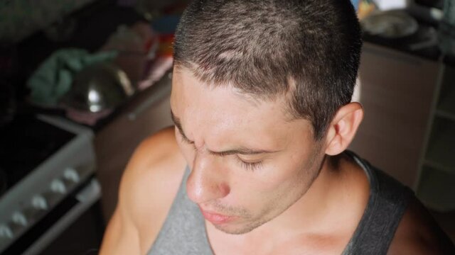 Young guy smokes an electronic cigarette at home. The man uses a vape. Bad habits. An alternative to tobacco