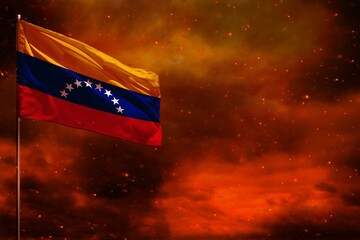 Fluttering Venezuela flag mockup with blank space for your text on crimson red sky with smoke pillars background. Troubles concept.