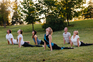 A group of people do yoga in the Park at sunset. Healthy lifestyle, meditation and Wellness