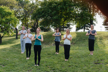 Obraz premium A group of people do yoga in the Park at sunset. Healthy lifestyle, meditation and Wellness