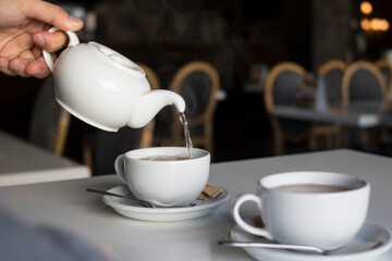 
The guy pours tea into a white cup from a white teapot
