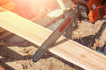 A carpenter saws a wooden Board with a chainsaw. Close-up