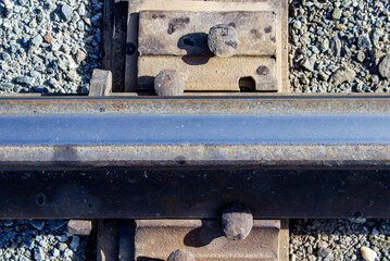 A metal rail is clogged to the wooden sleeper. Close-up of the railway