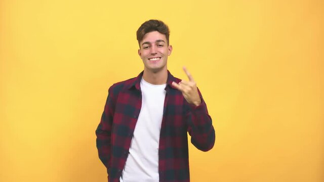 Young caucasian student man doing a rock gesture, enjoying life and laughing