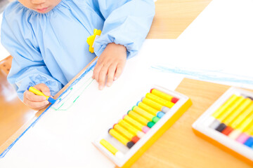 クレヨンで絵を描く幼稚園児の手元