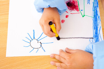 クレヨンで絵を描く幼稚園児の手元