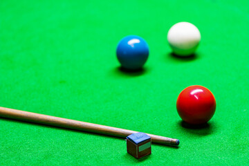 A cue and snooker balls of various colors are placed on the snooker table.