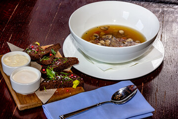 Mushroom clear soup in a plate and rye bread croutons