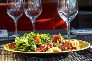 Salad of lettuce leaves, fried tuna, eggs is on the plate