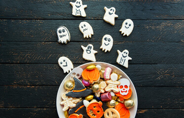Halloween Jack o Lantern candy bowl with candy and halloween cookies Trick or Treat on black wooden background