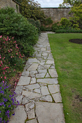 A crazy paving walkway between a flower bed and a lawn in an English country garden