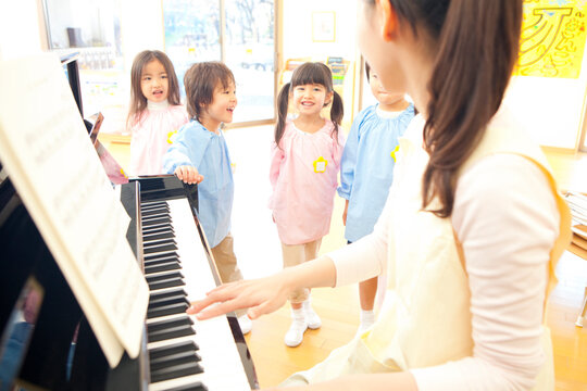 ピアノを弾く先生と歌う幼稚園児