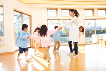 輪になって踊る幼稚園教諭と幼稚園児