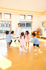 輪になって踊る幼稚園教諭と幼稚園児