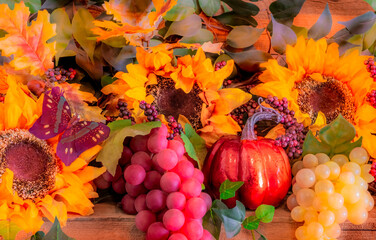 Sunflowers, grapes, and pumpkins glow in the morning sun on a  Autumn mantel with a butterfly.