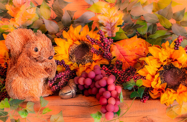 A squirrel joins Sunflowers, grapes, and fall foliage to fill a decorated Thanksgiving mantel.