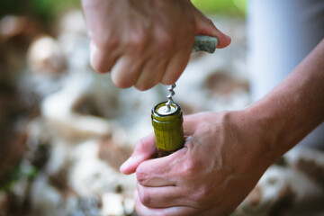Hands of a man opening a wine bottle with a corkscrew