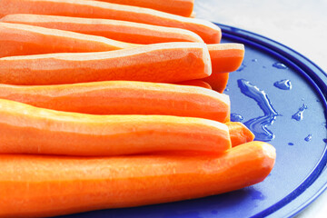 Peeled carrots on a blue plastic plate, selective focus.