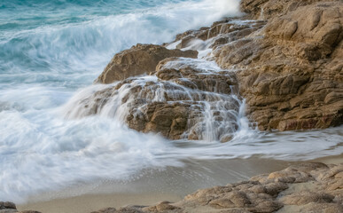 Long exposure photograph of waves  and water flowing from the stones at the sand beaches of Ikaria, Island in the Aegean Sea, Greece