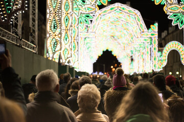 Fototapeta na wymiar A crowd gathered in George Street, Edinburgh's City Center, Scotland, UK, watches the light show taking place during the events held in the city during the festive period.
