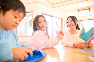 折り紙を折る幼稚園児と幼稚園教諭
