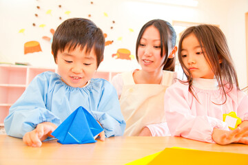 折り紙を折る幼稚園児と幼稚園教諭