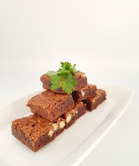 Chocolate brownies in a serving dish on a white background.