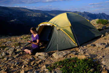 Blode hair woman relaxing outside of a tent using her phone. © roberjzm