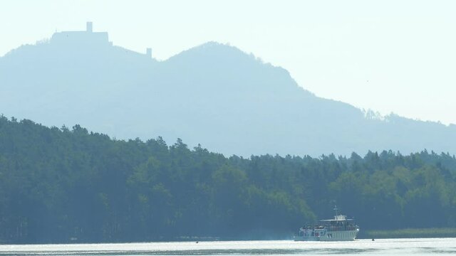 Steam ship named Maj with tourist on board on Machovo lake with Bezdez castle at background. Popular summer resort.