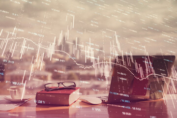 Double exposure of financial chart drawings and desk with open notebook background. Concept of forex market