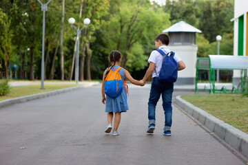two schoolchildren, a little girl and a boy with backpacks run on the way to green street