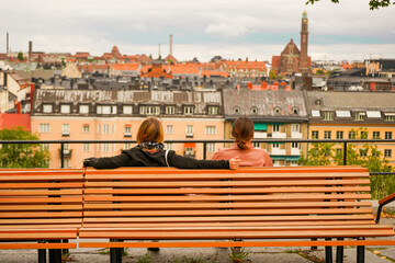 Two women sitting down in a bench looking and relaxing with the views of Stockholm Sweden