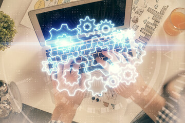 Double exposure of man's hands typing over computer keyboard and business theme hologram drawing. Top view. Financial markets concept.