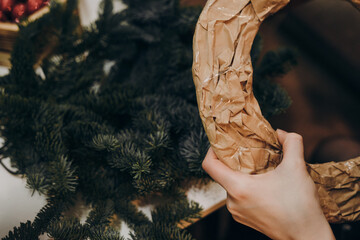 Woman making christmas wreath. Creating a Christmas wreath of spruce branches and a cardboard frame.