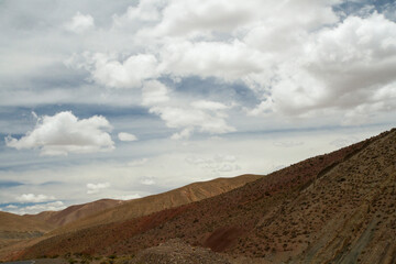 Desert landscape. View of the arid hills and brown valley under a beautiful summer sky with white clouds.