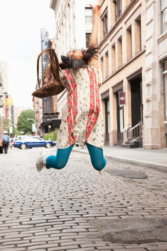 Japanese woman jumping for joy on city street
