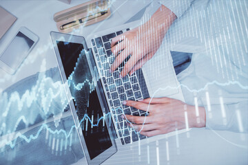 Double exposure of woman hands working on computer and forex graph hologram drawing. Top View. Financial analysis concept.