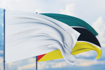 White flag on flagpole waving in the wind and flag of Mozambique. Closeup view, 3D illustration.