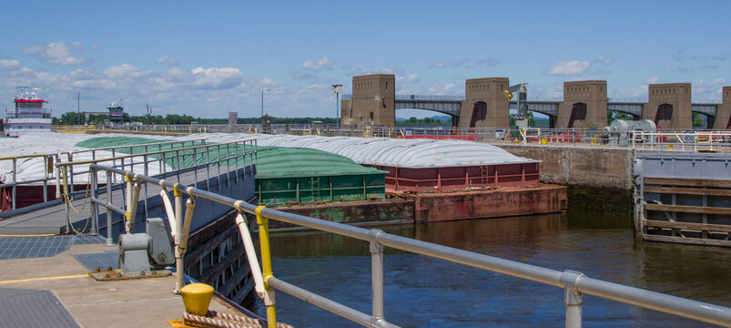 Lock Gates Opening:  Exit gates swing inward, allowing a towboat to guide three rows of covered barges through a lock on the Mississippi River.

