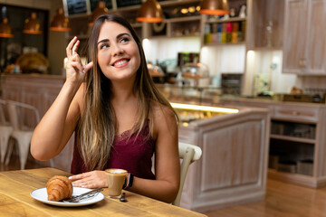 Young woman drinking coffee, making the sign of listening.