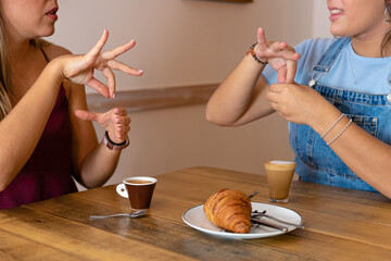 Detailed drawing of two young women drinking coffee and speaking in sign language.