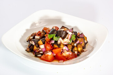 Fried eggplant salad with tomatoes and onions is on the plate