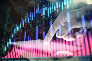 Double exposure of man's hands holding and using a digital device and forex graph drawing. Financial market concept.