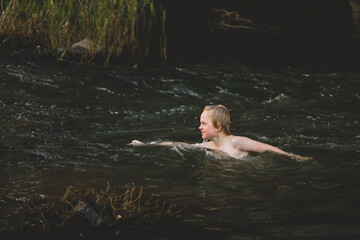 Boy swimming in fresh water river with at dusk in New South Wales, Australia