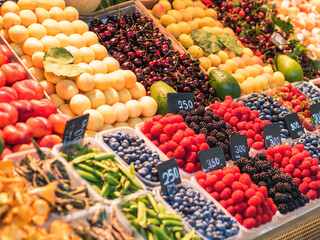 Fruit stand in the market. Sale of fresh exotic and local fruits and berries - raspberries, blackberries, peaches, apricots, avocados.