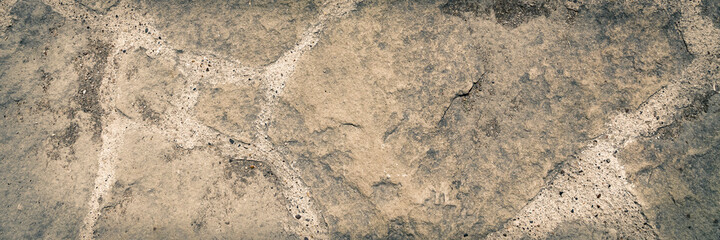 Stone pavement. Texture of stone paved ground. Large jagged stone blocks on a pedestrian sidewalk or road. Ancient masonry. Wide panoramic texture for background and design.