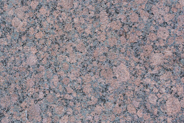 Granite texture. Natural pink granite with a grainy pattern. Stone background. Solid rough surface of rock. Durable construction and decoration material. Close-up.