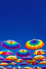 Fototapeta na wymiar Rainbow Colored Umbrellas Levitating On The Background Of A Blue Sky